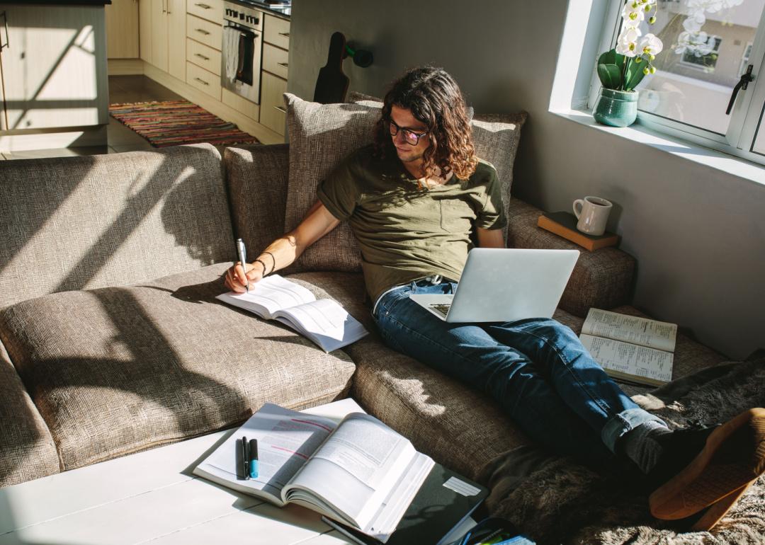 Student studying with textbooks and laptop at home.