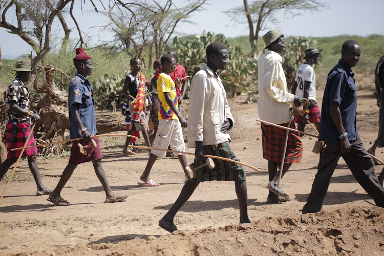 Pokot residents armed with sticks and swords walk along Chemelil-Riongo footpath in Tiaty, Baringo.