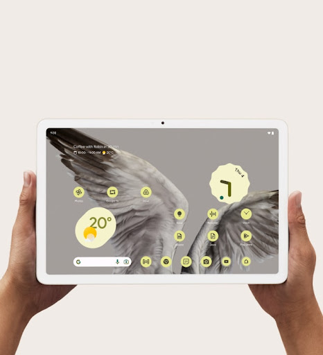 Two hands holding the Pixel Tablet with weather and time shown on front display.