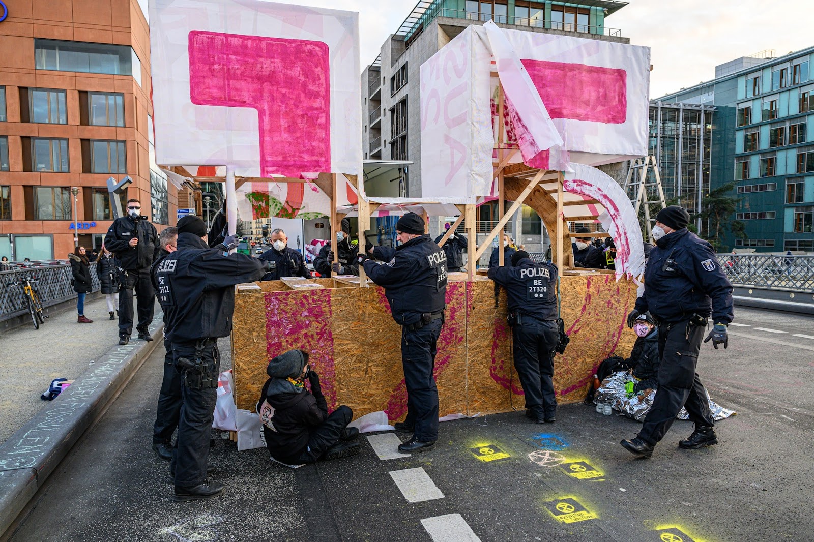 Police rip the paper facade of a large wooden structure of the numbers 1.5, on a Berlin bridge