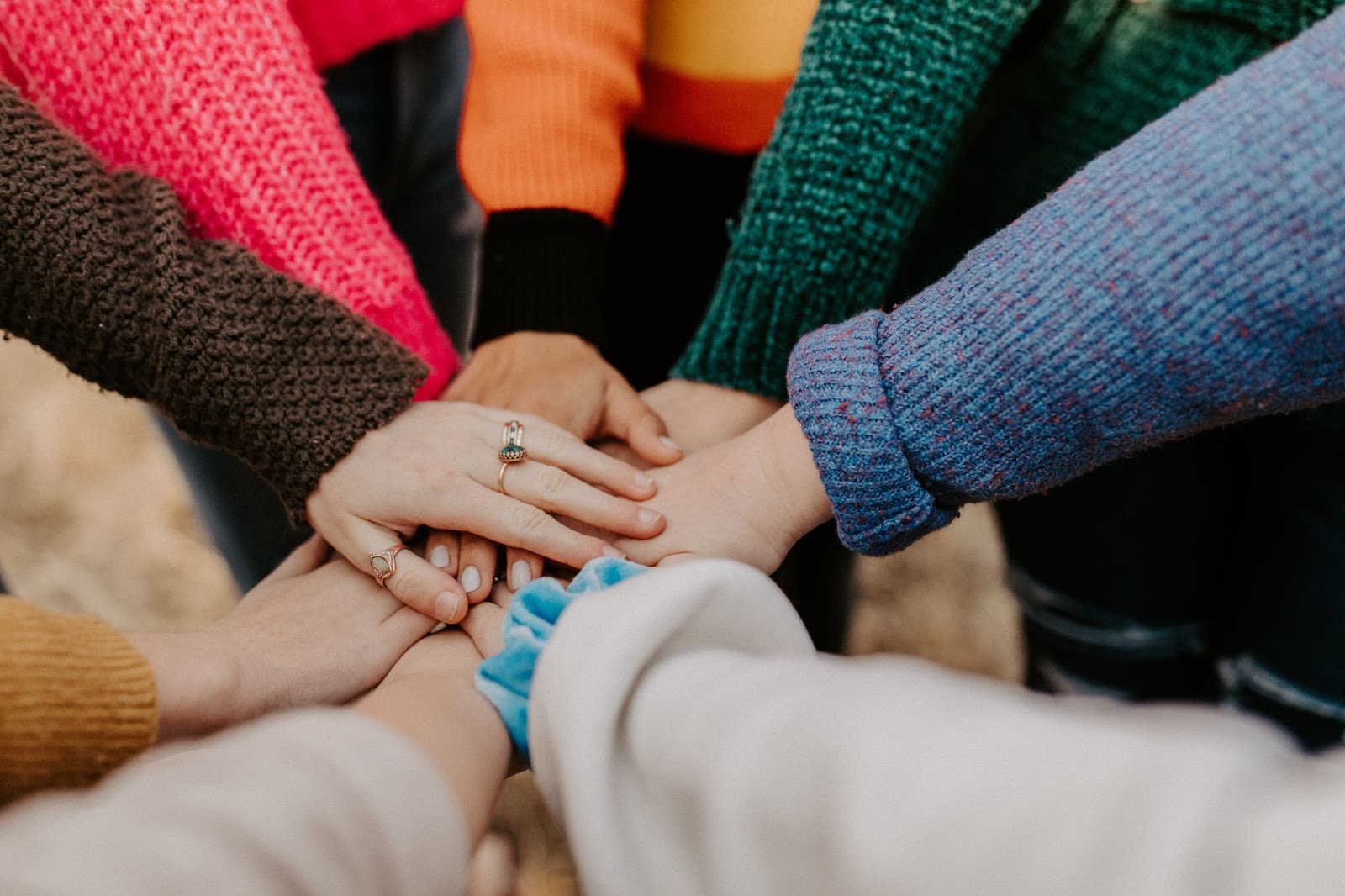 Image of hands put together in the centre of a circle of people