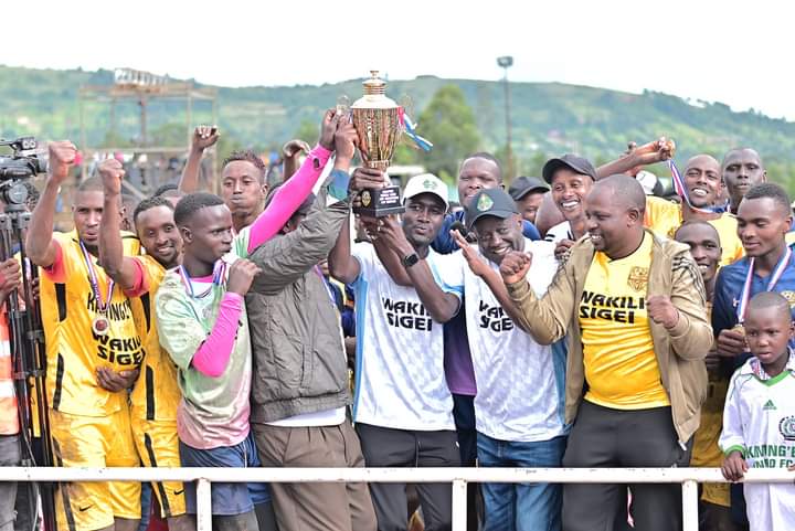 Bomet Senator Hillary Sigei present a trophy to Kamungei FC players