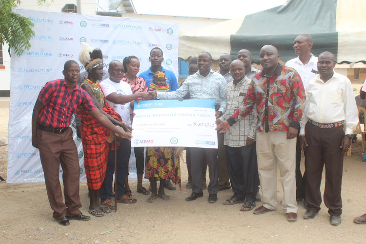 The USAID Feed the Future Livestock Market System team and Turkana county officials display the Sh20.6million cheque grant for the Social and Behaviour Change to encourage pastoralists to adopt good practices.