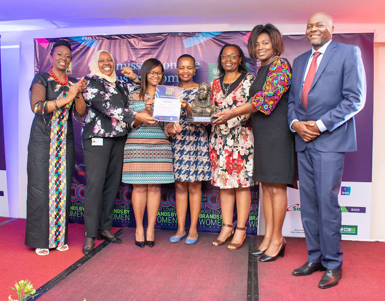 Rachel Shebesh, Cabinet Administrative Secretary, Public Service and Gender presents the top award to the safaricom team after they emerged 1st on the Top 100 Most Loved Brands by Women In Kenya 2022 Study Ranking. Looking on are Eva Muraya, CEO & Founder BSD Group (far left) and Chris Githiaga, Country Manager, Ipsos Ltd (far right). March 22, 2022.