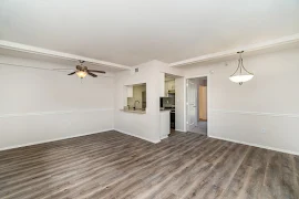 Open concept living and dining area with wood plank flooring, tan walls, white trim, and fixtures above the living room and dining area 