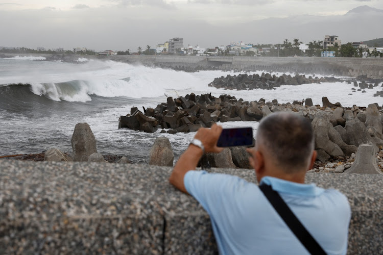 A man takes pictures of the waves breaking on the shore near the Fugang fishing harbor as Typhoon Koinu approaches, in Taitung, Taiwan, on October 4 2023. Picture: CARLOS GARCIA RAWLINS/REUTERS