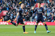 Phil Foden of Manchester City celebrates with teammate Joao Cancelo after he scores to make it 3-1 in the FA Cup quarterfinal against Southampton at St Mary's Stadium in Southampton on March 20 2022.