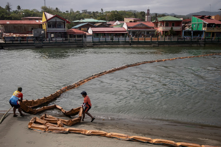 Coast guard personnel set up a floating boom to contain the oil spill from the sunken fuel tanker MT Princess Empress in the coastal town of Pola, Oriental Mindoro province, Philippines, March 6, 2023.