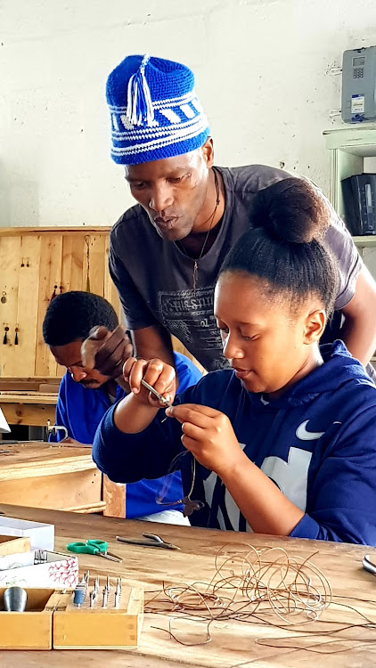 JEWELLERY-MAKING SKILLS: Izandla Zethu programme facilitator Luvuyo Phongolo works with trainee Phelani Makinana at the Masifunde Learner Development initiative, where a bracelet has been nominated for the prestigious national award for Most Beautiful Object in SA by Design Indaba