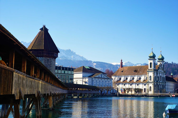 Chapel Bridge along the riverfront in Lucerne, Switzerland, with the Jesuit Church in the background. 