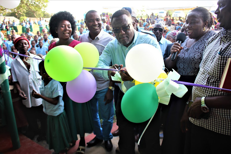 Kilifi Deputy governor Gideon Saburi cuts the tape to officially open two ECD classrooms at Tunzanani primary school on Saturday