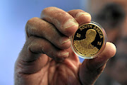 Ahmed Kathrada holding a coin launched by South African Mint and Nelson Mandela Foundation in  2014 in Johannesburg. Today  some buyers of the coins are complaining that they have been deceived by Gold for Life who allegedly sell them the coins under the pretence of investment but only to find out later that they had been tricked  by the company./ GALLO IMAGES