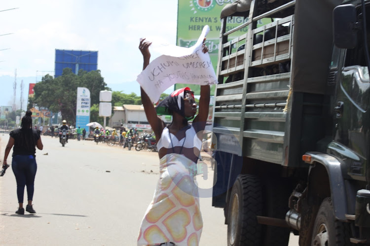 Azimio La Umoja supporter carries placard written "Dear Commander In Chief Uchumi Umechemka na Youths Hawana Janta" as he protests peacefully along Kisumu-Kakamega on May 2, 2023.