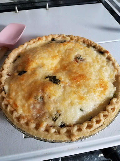 a pie with a pink silicon spoon on a white surface,