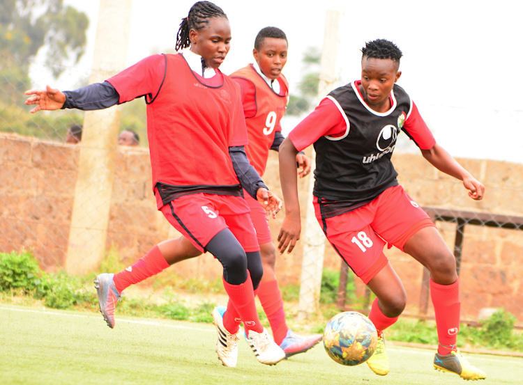 Harambee Starlets' Cynthia Shilwatso (R) charges past Dorcas Shikobe and Wincate Kaari in a past training session