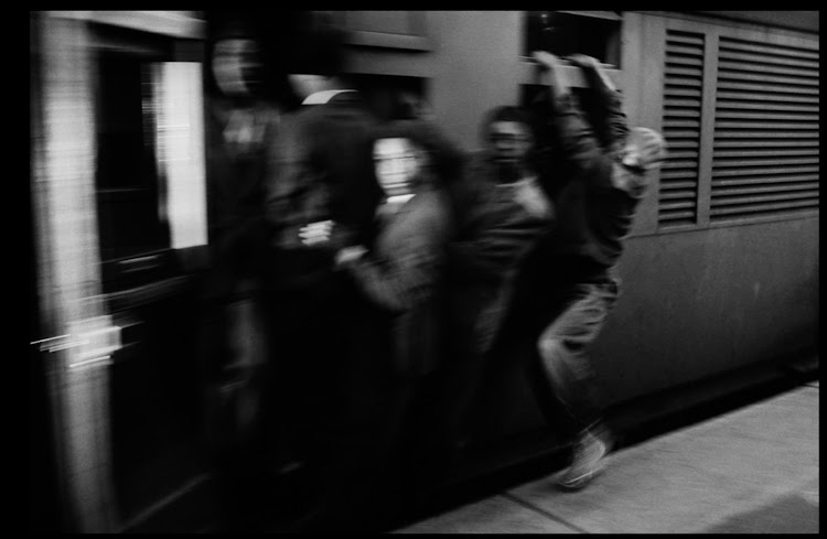 Train accelerates with its load of clinging passengers. They ride like this through rain and cold, some for the entire journey.