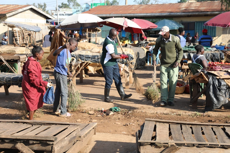 Vihiga Environment chief officer Richard Boiyo joins county workers in cleaning Luanda town market in September 2023.