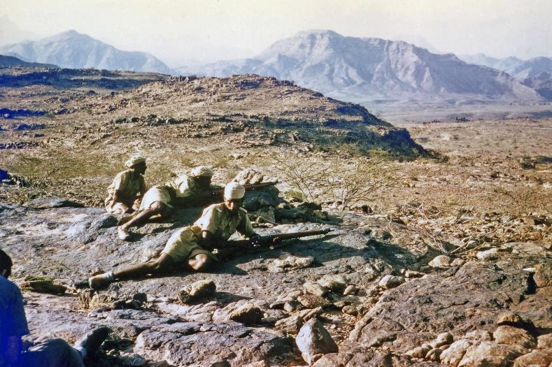 A group of people sitting on a rocky hill with mountains in the background Description automatically generated with low confidence