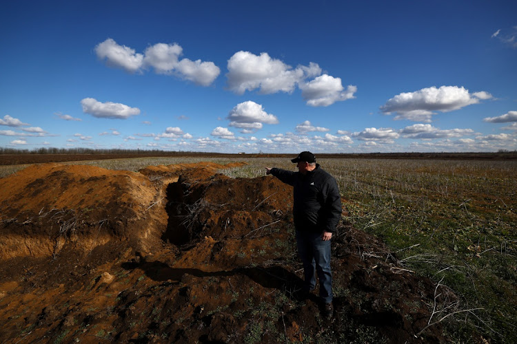 Grain farmer Oleksandr Klepach points at trenches in his field, amid Russia's invasion of Ukraine, in Snihurivka, southeast Ukraine.