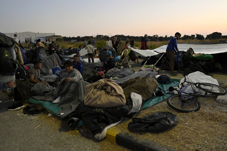 Refugees rest on the side of a road after a massive fire destroyed Moria refugee camp on the island of Lesbos on Tuesday.