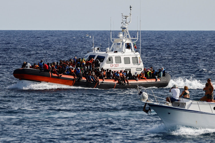 An Italian Coast Guard vessel carrying migrants rescued at sea passes near a tourist boat, on the Sicilian island of Lampedusa, Italy, September 18, 2023.