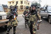 Seleka rebel alliance fighters in front of the presidential palace in Bangui, Central African Republic. The rebels' leader yesterday pledged to name a power-sharing government to defuse international criticism of the coup that killed 13 South African soldiers