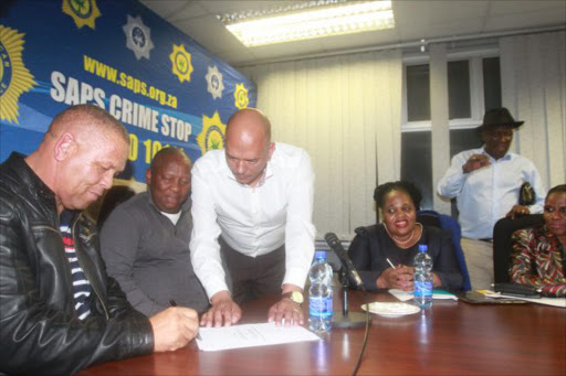 Police Minister Bheki Cele (Right with hat on ) looks on as Uncedo Service Taxi Association president Ntsikelelo Gaehler (LEFT) and Border Alliance Taxi Association president Vuyani Mshiywa (centre) shake hands on Friday night in Mthatha after signing the peace agreement which saw Cele lifted the ban on taxi operations in Mthatha and surrounding areas. Picture:LULAMILE FENI