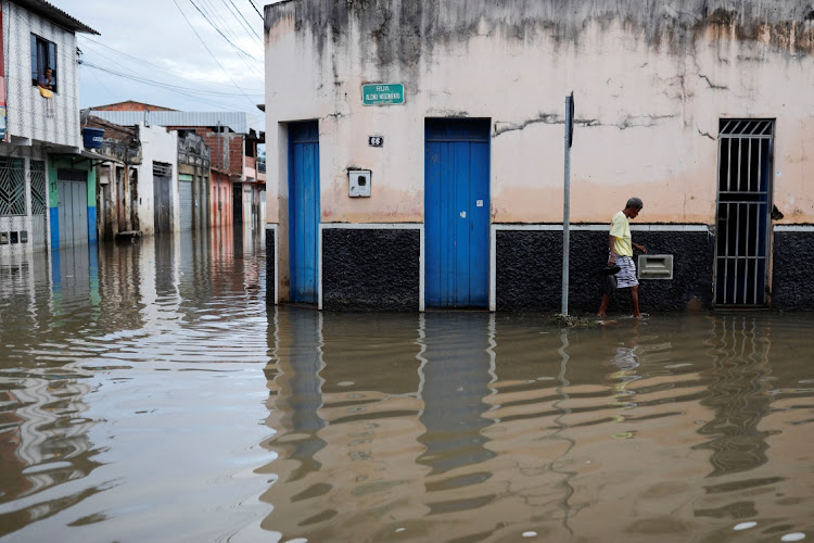 A person walks through the water along a street during floods caused by heavy rain in Itajuipe, Bahia state, Brazil December 27, 2021.