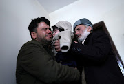 Hamid Safi, a 29-year-old taxi driver who had found baby Sohail Ahmadi in the airport, cries as he hands over Sohail to his grandfather Mohammad Qasem Razawi in Kabul, Afghanistan, January 8, 2022.