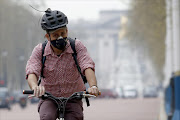 A cyclist wears a mask as he cycles near Buckingham Palace in London. REUTERS/Luke MacGregor