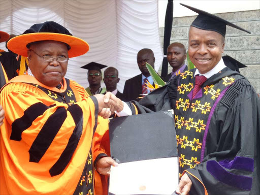 Architect Dr Reuben Musyoka Mutiso given his degree by CS Transport and Chairman University Governing Council Michael Kamau after he was conferred Honorary Doctor of Management and Leadership Degree.