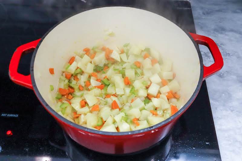 Cooking Garlic, Diced Vegetables, And Potatoes In A Dutch Oven.