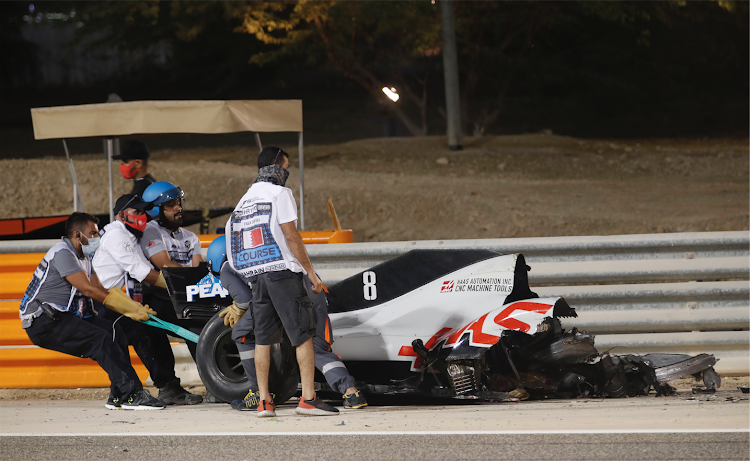 Stewards attempt to clear the car of Haas' Romain Grosjean from the track following a crash