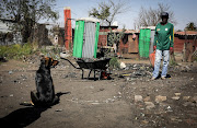 19 August 2019:  A man and his dog are seen cleaning the filth around his shack.  