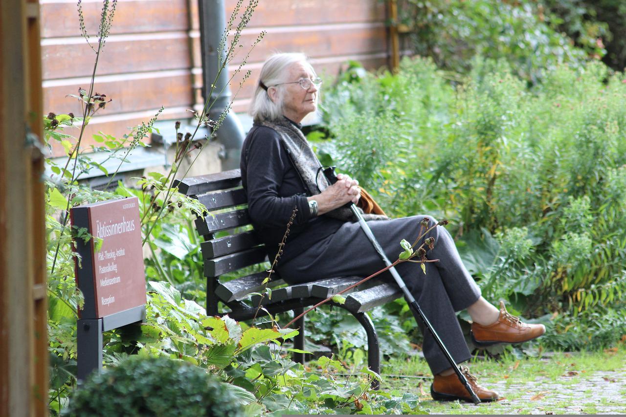 vieille femme assise sur une chaise et tenant une canne