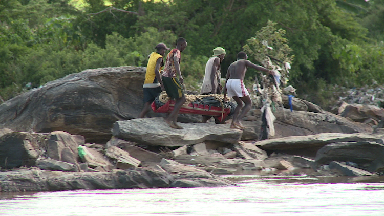 Divers carry the body of one of the four men who drowned in River Athi on Tuesday last week