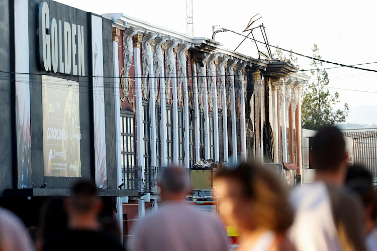 People gather near the damaged facade after adjoining nightclubs caught fire in Murcia, Spain, October 1 2023. Picture: EVA MANEZ/REUTERS