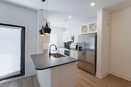 Kitchen with black granite countertops, stainless steel appliances, black subway tile backsplash, and white cabinets