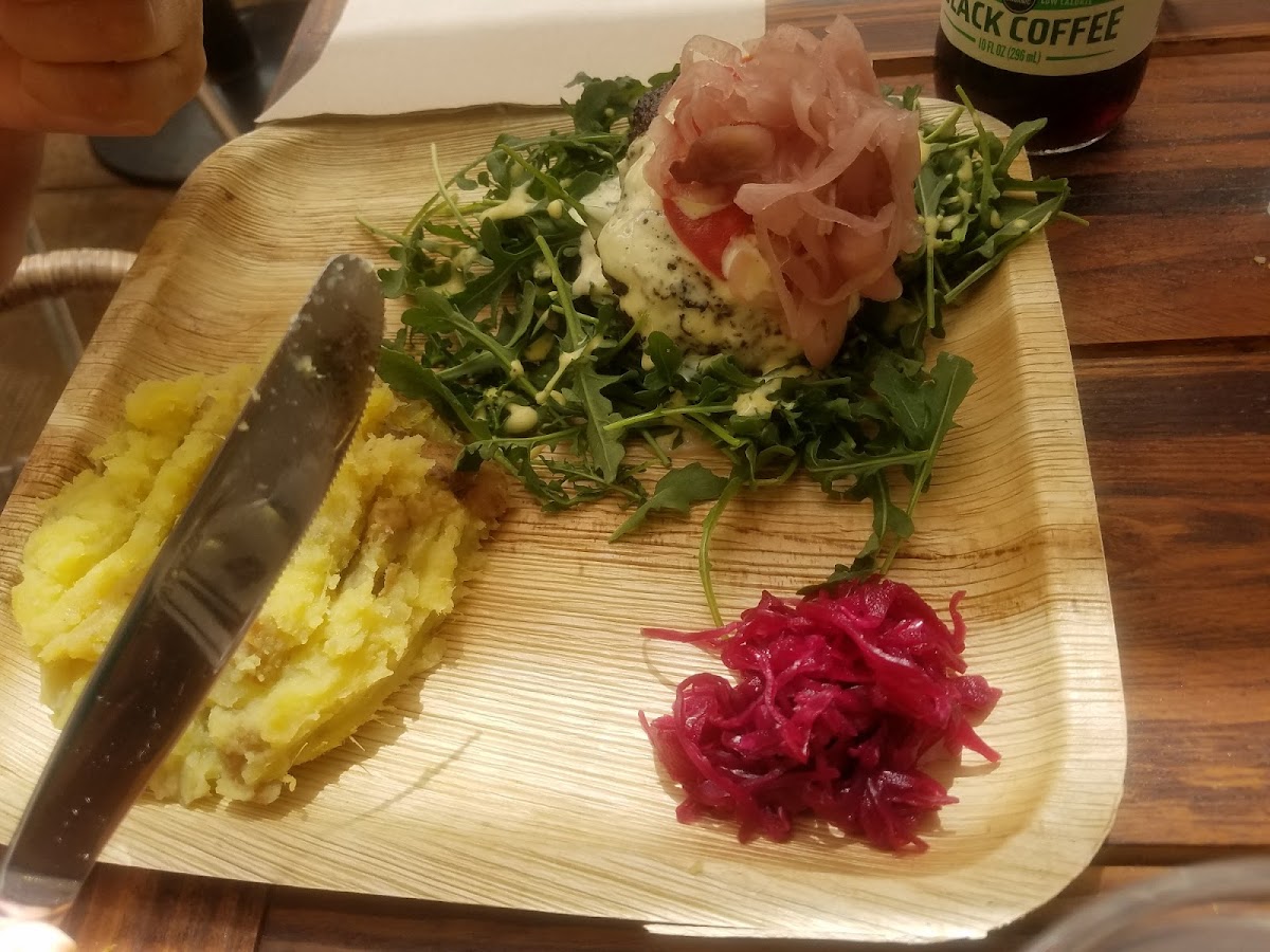 Bison burger on greens with a side of mashed potatoes and pickled onions.