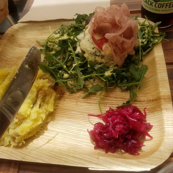 Bison burger on greens with a side of mashed potatoes and pickled onions.