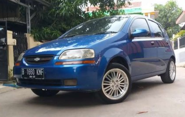 Gambar ini menunjukkan mobil Chevrolet Aveo 2004 biru tampak depan dan samping kiri