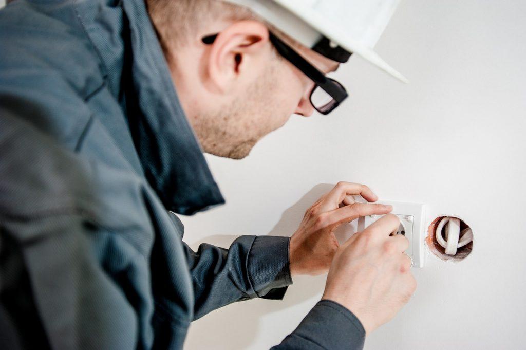 An electricitian fixing a power outlet.