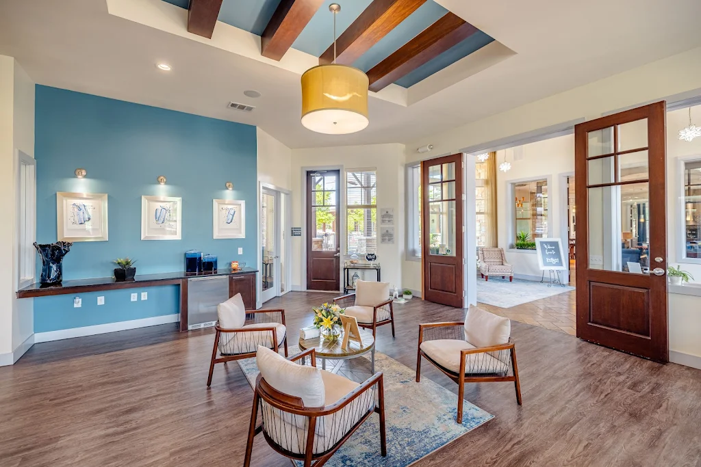 Seating area in the clubhouse with wood-inspired flooring, modern seating, and ceiling beams with a light fixture