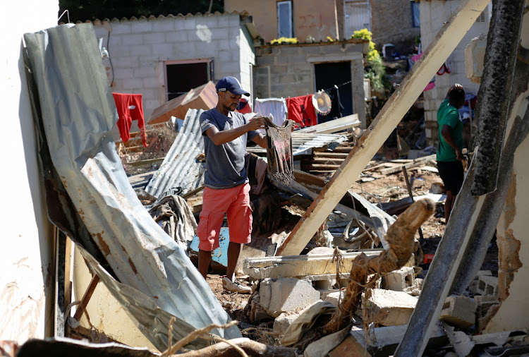 A man looks at a shirt belonging to a missing girl as he and other residents sift through rubble, looking for bodies, after heavy rains caused flooding in Ntuzuma near Durban.