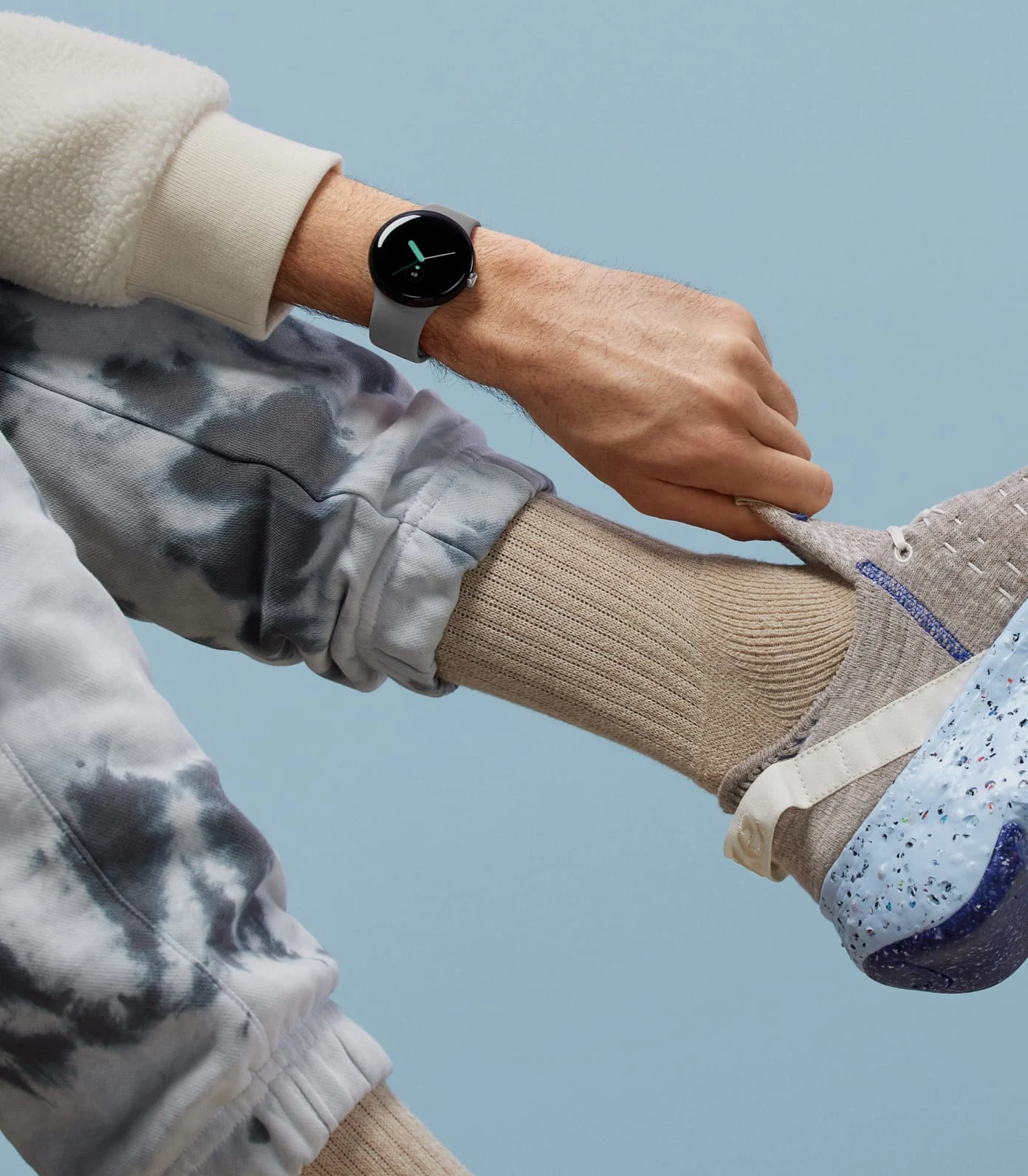 A person wearing a Google Pixel Watch pulls on their athletic trainers