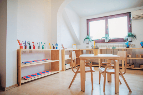 The interior of a modern preschool classroom with wooden furniture and colorful art supplies