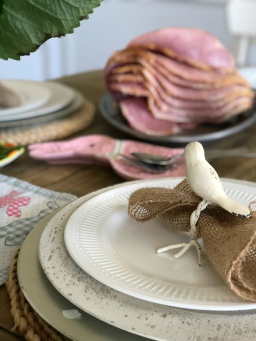 A fall decorated table with plates and a sliced ham resting on it.