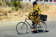 A man seen riding a bicycle while warmly wrapped in a blanket at Letlhabile, as temperatures drop inland. 