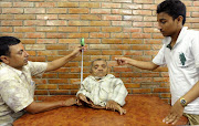 In this photograph taken on September 17, 2013, Master Nau, a 73-year-old Nepali, who claims to be the world's shortest man in the Guinness World Records' immovable category, sits on top of a table as as he is measured in Kathmandu.