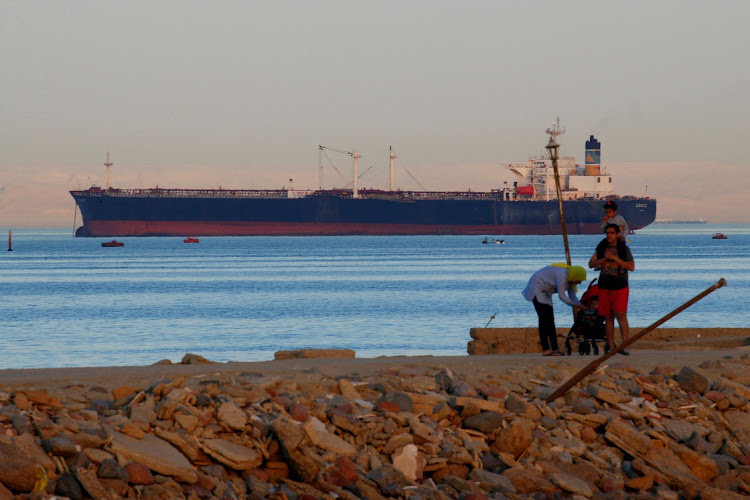 People walk on the beach as a container ship crosses the Gulf of Suez towards the Red Sea before entering the Suez Canal, in El Ain El Sokhna in Suez, east of Cairo. File photo: AMR ABDALLAH DALSH/REUTERS